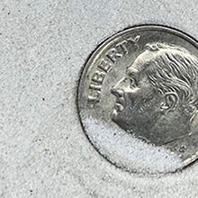 Close-up of a coin with 'Liberty' inscribed on a textured surface